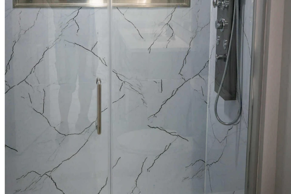 Marble-patterned shower with glass door enclosure.