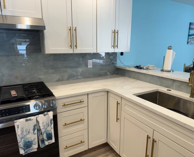 Modern kitchen with white cabinets and backsplash.