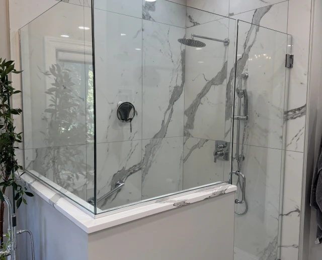 Glass shower with marble-patterned walls.