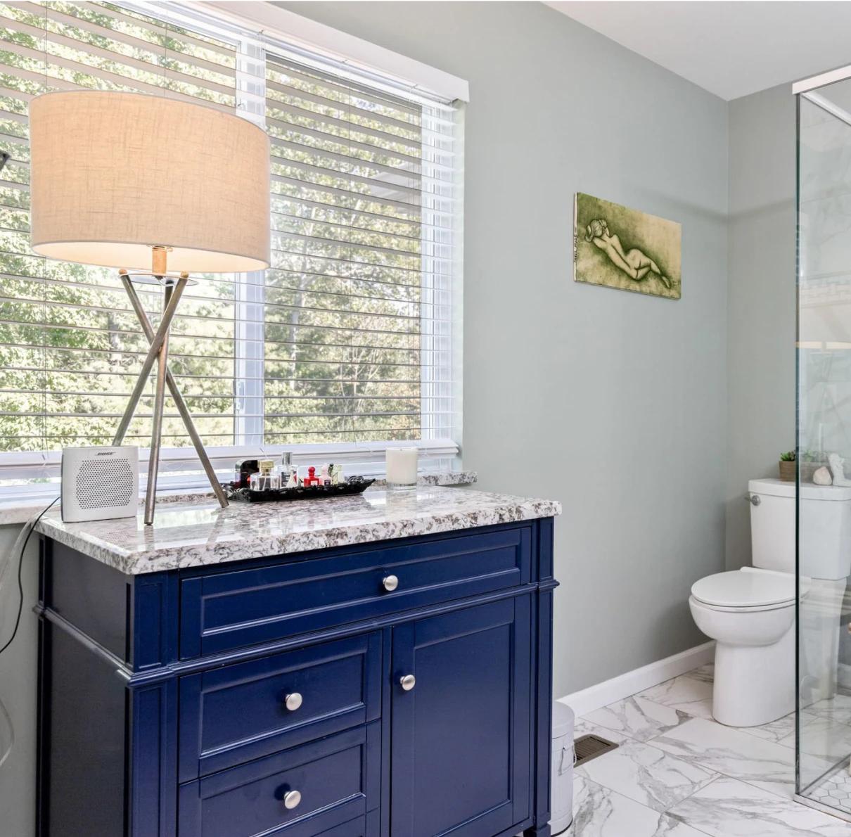 Modern bathroom with navy vanity and lamp.
